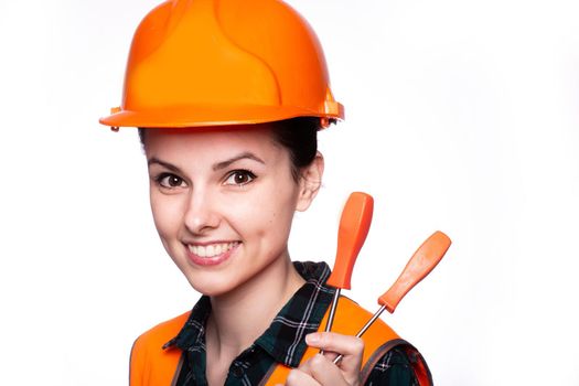 a woman in a construction helmet, and an orange vest holds a construction tool in her hand, white studio background, close-up portrait. High quality photo