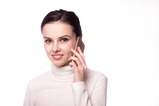woman in a white turtleneck talking on the phone, portrait on a gray background. High quality photo