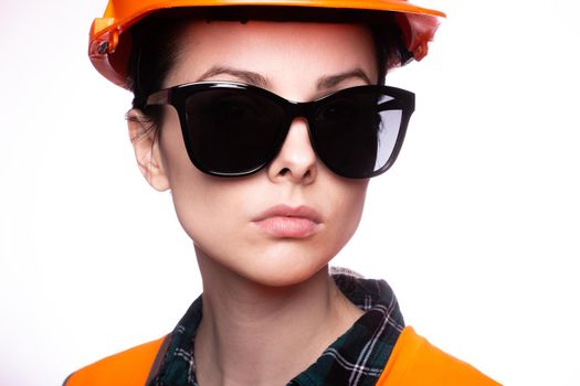 woman in sunglasses construction safety helmet and orange vest, close-up portrait. High quality photo