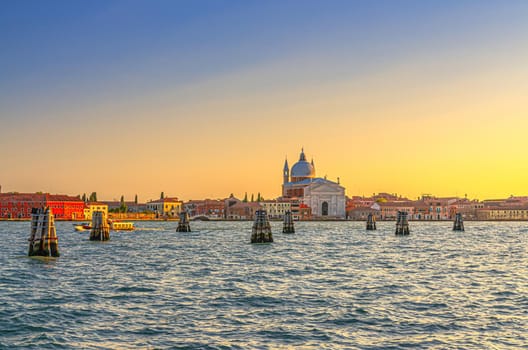 Chiesa del Santissimo Redentore catholic church and row of buildings on fondamenta embankment of Giudecca island canal in Venetian Lagoon, sunset view from Venice city, Veneto region, Northern Italy