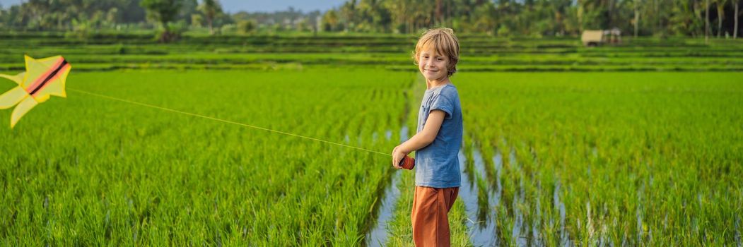 Tourist boy launches a kite in a rice field. Traveling with children concept. Kids friendly place. BANNER, LONG FORMAT