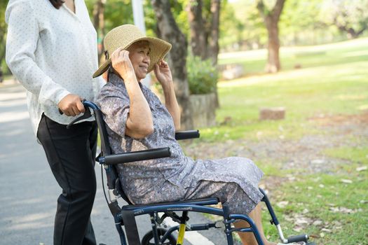 Caregiver help and care Asian senior or elderly old lady woman patient sitting and happy on wheelchair in park, healthy strong medical concept.