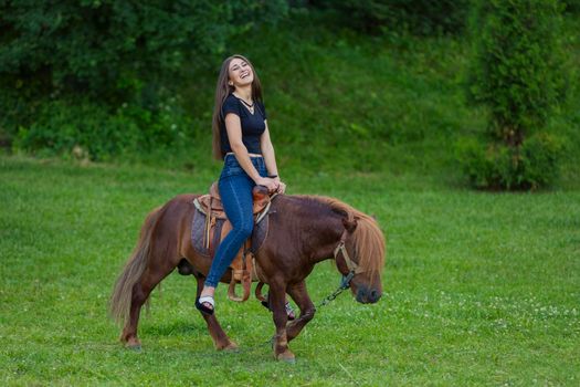 girl riding a pony on a green lawn