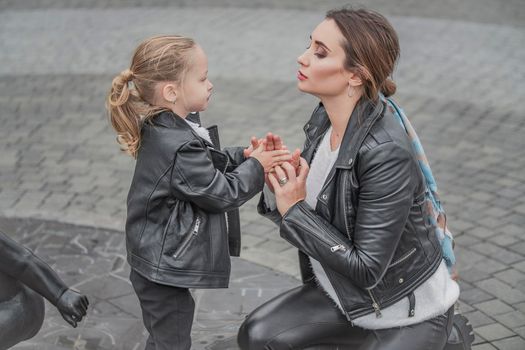 mother plays with her daughter in the city on the square