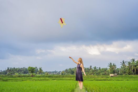 Young woman tourist launches a kite in a rice field in Ubud, Bali Island, Indonesia.