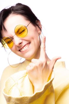 brunette woman in yellow glasses and yellow sweater, close-up portrait, white background. High quality photo