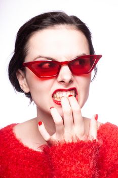 emotional brunette woman in red sunglasses, red nails, red lipstick, white background. High quality photo