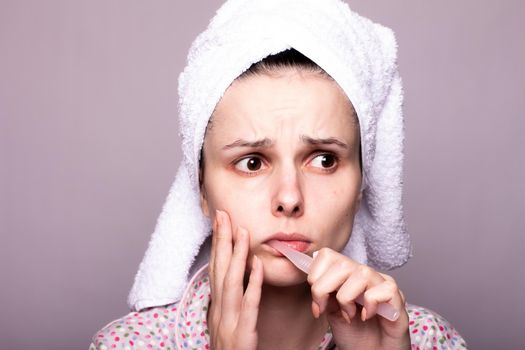 a woman in a towel on her head brushes her teeth, gray background, close-up. High quality photo