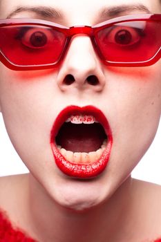 brunette woman in red glasses with red lipstick on her lips, her teeth are painted in lipstick, close-up portrait. High quality photo