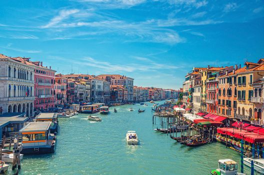 Venice cityscape with Grand Canal waterway. View from Rialto Bridge. Gondolas, boats, vaporettos docked and sailing Canal Grande. Venetian architecture colorful buildings. Veneto Region, Italy.