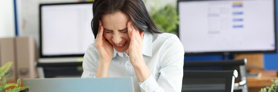 A young woman in the office is suffering from a headache. Anxiety and burnout at work. Stress and tension