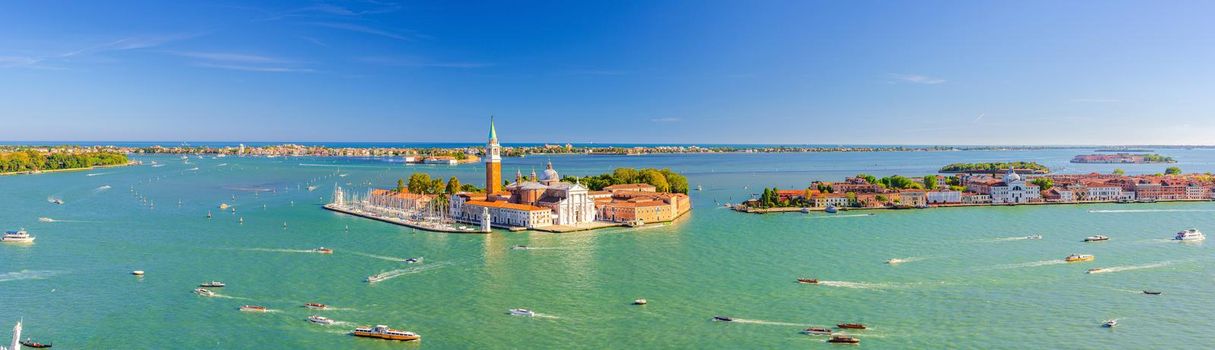 Aerial panoramic view of Venetian Lagoon with San Giorgio Maggiore island, Lido island and Giudecca island, sailing boats in Giudecca Canal, blue sky, Venice city, Italy. Panoram of Venetian Lagoon