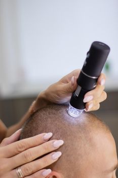 Trichology. Doctor diagnoses the structure of the hair. Consultation with a trichologist. Modern optical diagnostic equipment in dermatology and trichology clinic.
