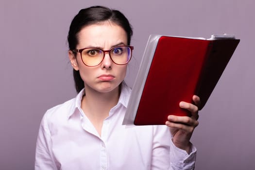 woman in a white shirt and glasses holds a red notebook in her hand. High quality photo