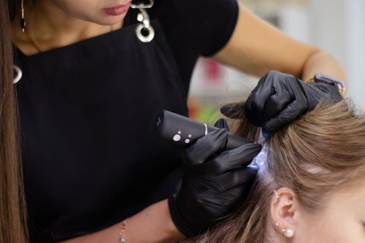 Trichological and dermatological examination of scalp and hair follicles condition of young female patient in cosmetology clinic. visiting dermatologist at clinic. trichology concept. close-up.