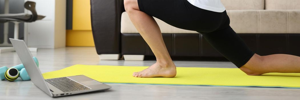 Woman doing stretching at home on a gymnastics mat, online workout. Relaxation after remote work, freelancer