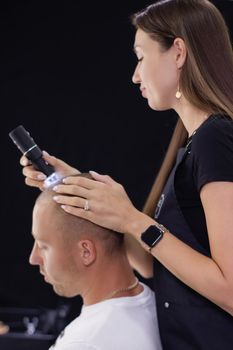 Trichoscope examination of hair, scalp and hair follicles of a young man. Copy space. The head of a man with thinning hair during the Trichology.