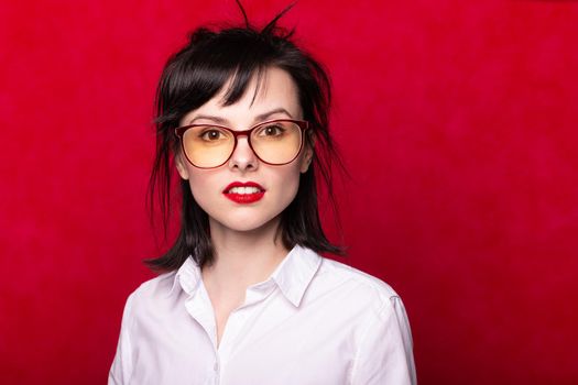 woman manager with red lips in a white shirt and glasses on a red background. High quality photo