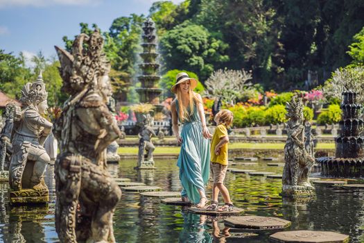 Mom and son tourists in Taman Tirtagangga, Water palace, Water park, Bali Indonesia. Honeymoon in Bali. Traveling with children concept. Kids friendly place.