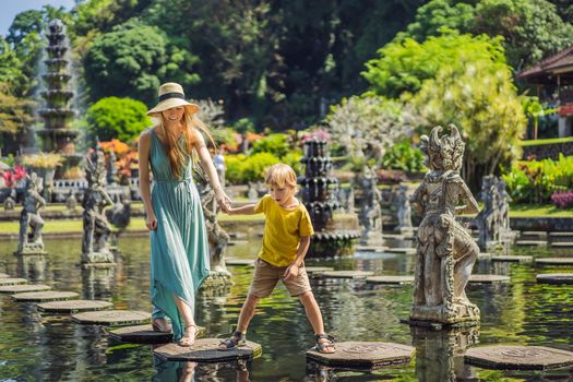 Mom and son tourists in Taman Tirtagangga, Water palace, Water park, Bali Indonesia. Honeymoon in Bali. Traveling with children concept. Kids friendly place.