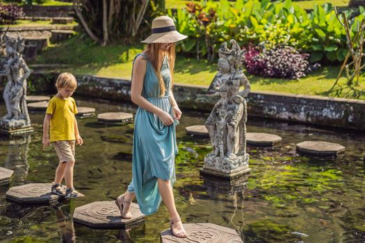 Mom and son tourists in Taman Tirtagangga, Water palace, Water park, Bali Indonesia. Honeymoon in Bali. Traveling with children concept. Kids friendly place.