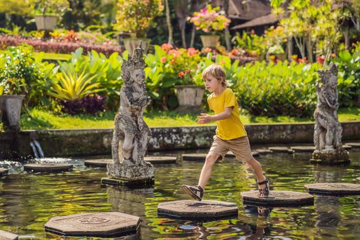 Boy tourist in Taman Tirtagangga, Water palace, Water park, Bali Indonesia. Honeymoon in Bali. Traveling with children concept. Kids friendly place.