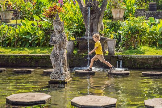 Boy tourist in Taman Tirtagangga, Water palace, Water park, Bali Indonesia. Honeymoon in Bali. Traveling with children concept. Kids friendly place.