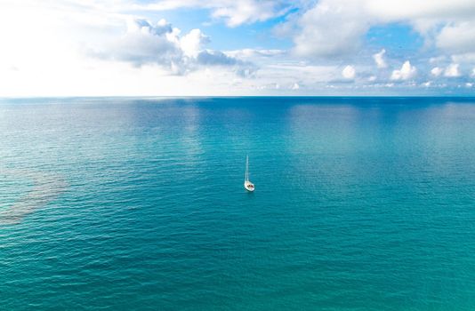 Aerial view of beautiful amazing Tyrrhenian sea with turquoise water, tropical seascape, endless horizon with bright blue sky and white clouds, small yacht background, Tropea, Calabria, Southern Italy