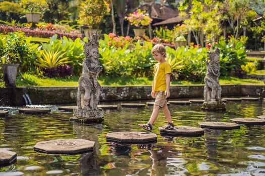 Boy tourist in Taman Tirtagangga, Water palace, Water park, Bali Indonesia. Honeymoon in Bali. Traveling with children concept. Kids friendly place.