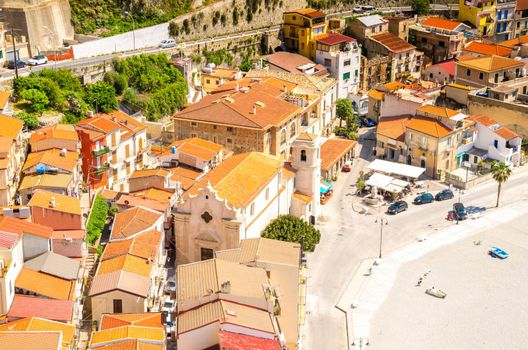 Top view of orange tiled roofs of colorful traditional typical italian houses, church and sandy beach in beautiful seaside town village Scilla, Calabria, Southern Italy
