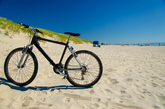 Bicycle bike on sandy yellow beach in front of blue sky in National Park Kursiu nerija, the Curonian Spit, Baltic sea, Lithuania