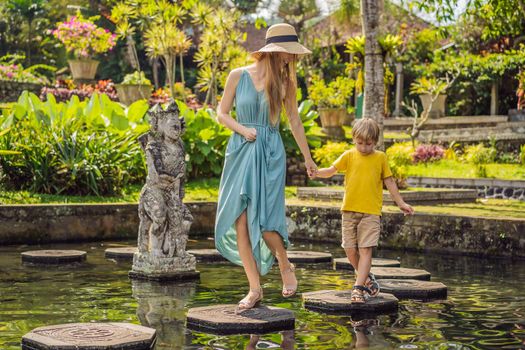 Mom and son tourists in Taman Tirtagangga, Water palace, Water park, Bali Indonesia. Honeymoon in Bali. Traveling with children concept. Kids friendly place.