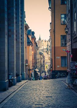 Traditional typical narrow streets with paving stones, cobblestone, lamps, cafes, restaurants, shops, bikes in old historical town quarter Gamla Stan of Stadsholmen island, Stockholm, Sweden