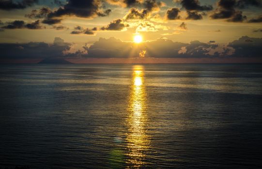 Aerial view of beautiful amazing sea sunset, ocean sunrise, seascape and endless horizon with color dramatic sky with clouds and volcanic hill mountain on background, Tropea, Calabria, Southern Italy