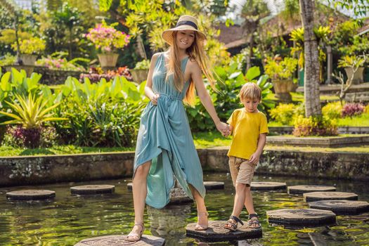 Mom and son tourists in Taman Tirtagangga, Water palace, Water park, Bali Indonesia. Honeymoon in Bali. Traveling with children concept. Kids friendly place.