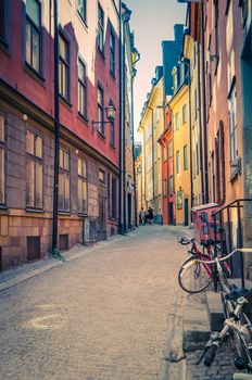 Traditional typical sweden narrow street with paving stones, bikes and colorful buildings in old historical town quarter Gamla Stan of Stadsholmen island, Stockholm, Sweden