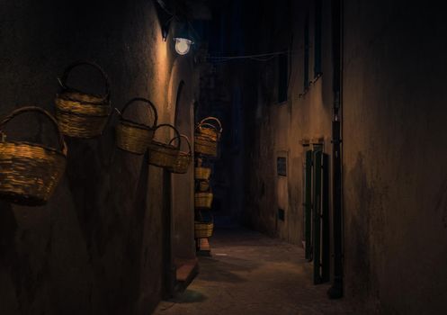 Night evening street with bright lanterns lamps and baskets on wall of building, Tropea town, Vibo Valentia, Calabria, Southern Italy