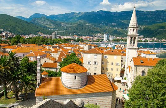 Panoramic view from citadel of Old town Budva with medieval buildings, red tiled roofs, chapel of Saint Ivan church, Holy Trinity church, marine, range of mountains and Adriatic Riviera, Montenegro