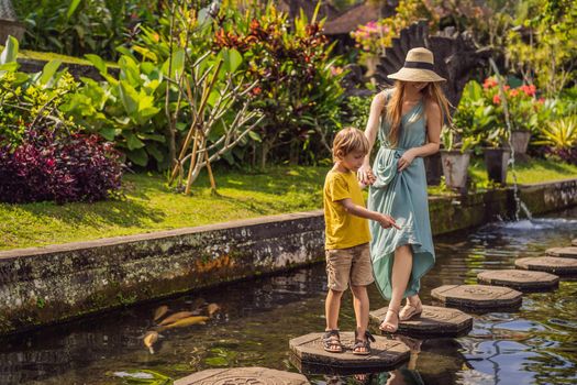 Mom and son tourists in Taman Tirtagangga, Water palace, Water park, Bali Indonesia. Honeymoon in Bali. Traveling with children concept. Kids friendly place.