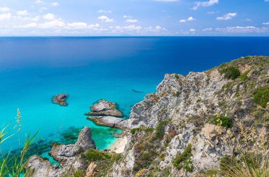 Aerial panoramic view of horizon and amazing tropical blue azure turquoise water of sea, rock cliff grass hill, Parco Belvedere platform Capo Vaticano, blue sky background, Calabria, Southern Italy