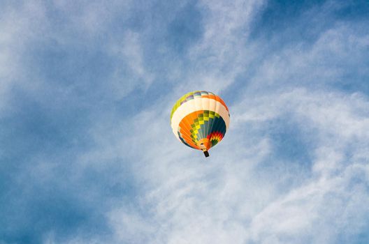 Colorful color hot air balloon in flight flying against blue sky with white clouds background with copy space