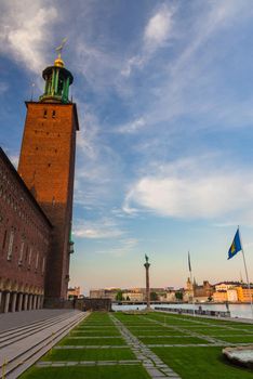 Stockholm City Hall (Stadshuset) tower building, Monument Engelbrekt, grass lawn in Park Stadshusparken on Kungsholmen Island in old town near Lake Malaren with blue sky, white clouds, Sweden