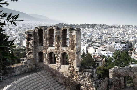 Panoramic view of white buildings city districts and The Odeon of Herodes Atticus stone theatre under Acropolis in Athens, Greece