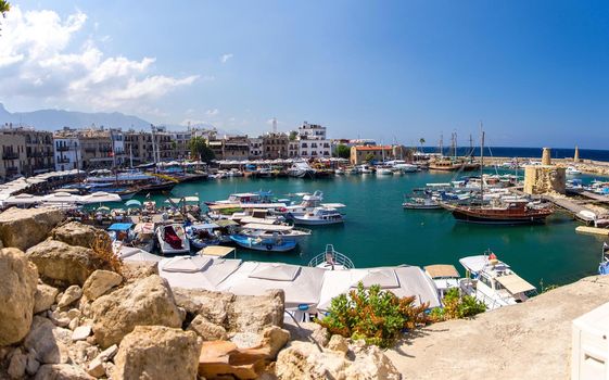 Panoramic view from old castle of marina harbour and port with yachts in Kyrenia Girne town against blue sky and mountains, North Cyprus