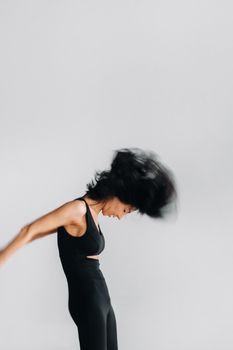 A blurry silhouette of a woman in black sportswear is engaged in dynamic kali meditation in the yoga hall.