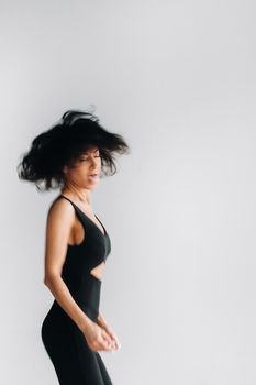 A blurry silhouette of a woman in black sportswear is engaged in dynamic kali meditation in the yoga hall.