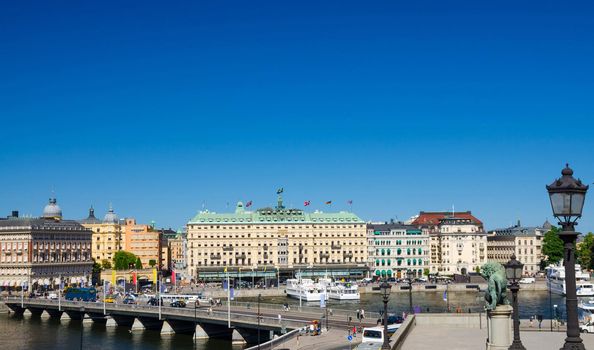 Aerial panoramic view of bridge, street lights lamp, lion statue monument, Lake Malaren harbour embankment with typical Swedish buildings and Grand Hotel with copy space, Stockholm, Sweden