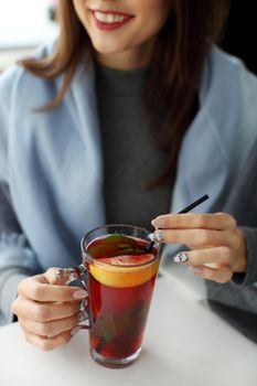 Hands of young woman holding a cup of hot mint tea or hot lemonade