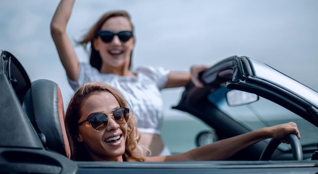 close up.two happy young women in a convertible car . fashionable lifestyle