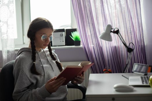 A young girl reads a school book. Gaining knowledge through school reading. A capable student. A young girl with braids.
